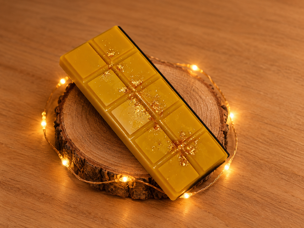 Tablette de fondant Café Viennois jaune doré, décorée de paillettes dorées, sur un rondin entouré d’une guirlande lumineuse.