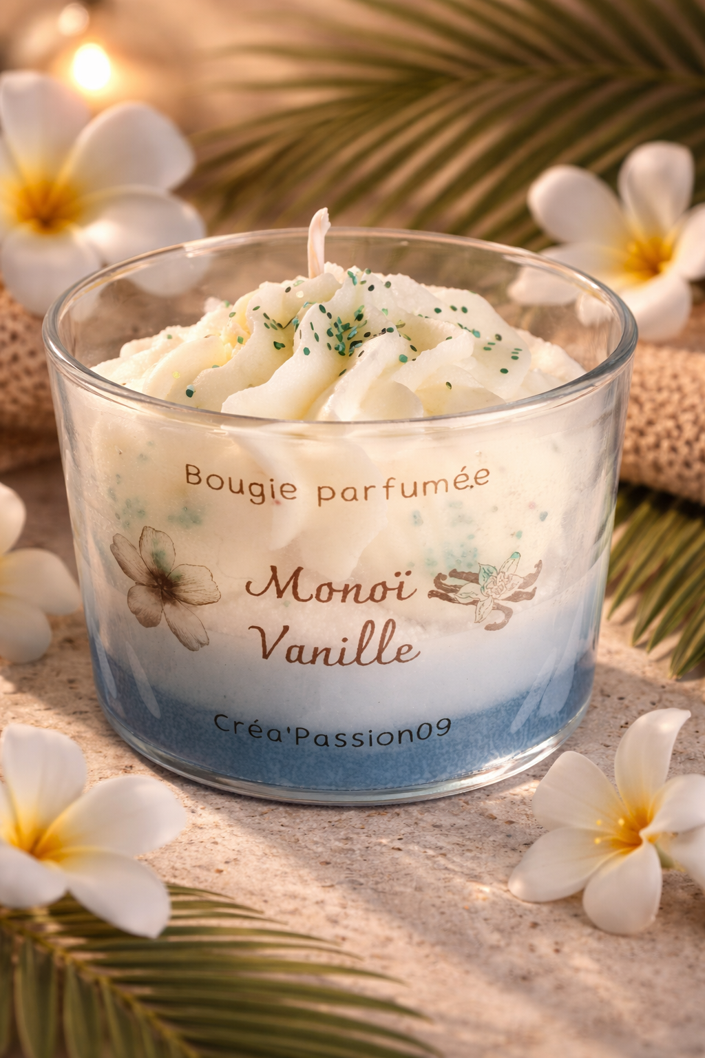 Bougie parfumée monoï vanille en verre transparent, cire végétale tourbillonnée avec paillettes, entourée de fleurs de tiaré sur sable - Créa’Passion09